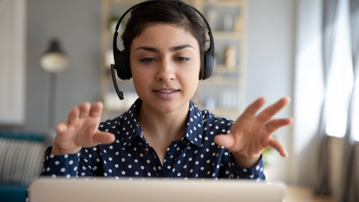 Lady with headset speaking in front of a screen