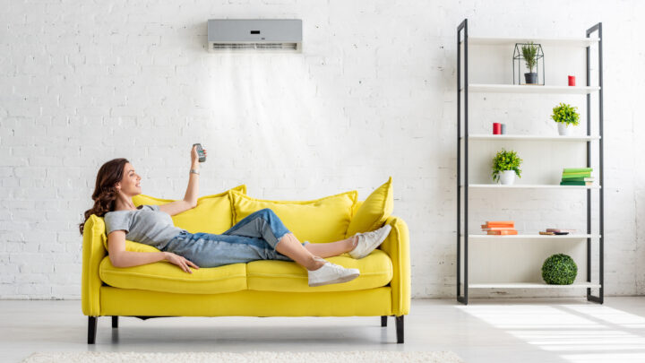 lady sitting on a yellow couch, activating the air conditioning