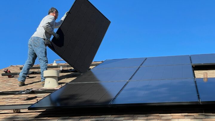 Worker on roof installing solar panels