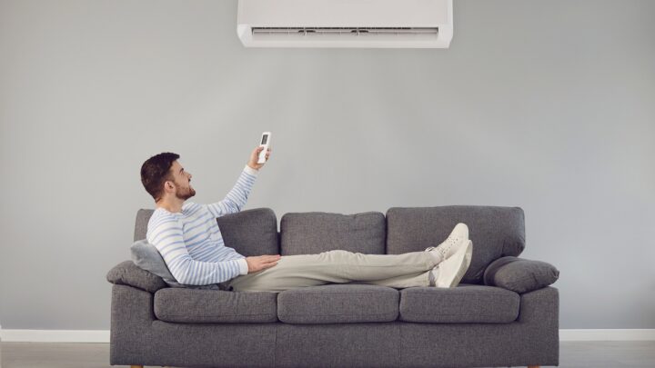 Man sitting on a sofa and activating air conditioner