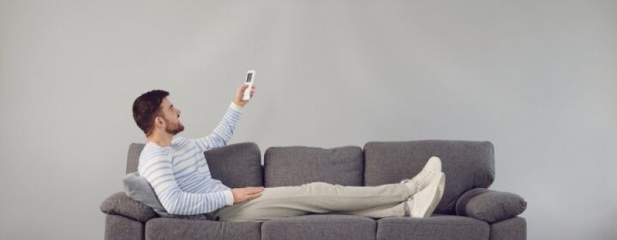 Man sitting on a sofa and activating air conditioner